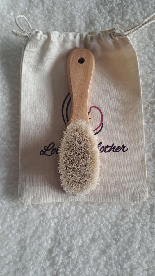 Wooden brush with natural bristles on a branded drawstring bag.
