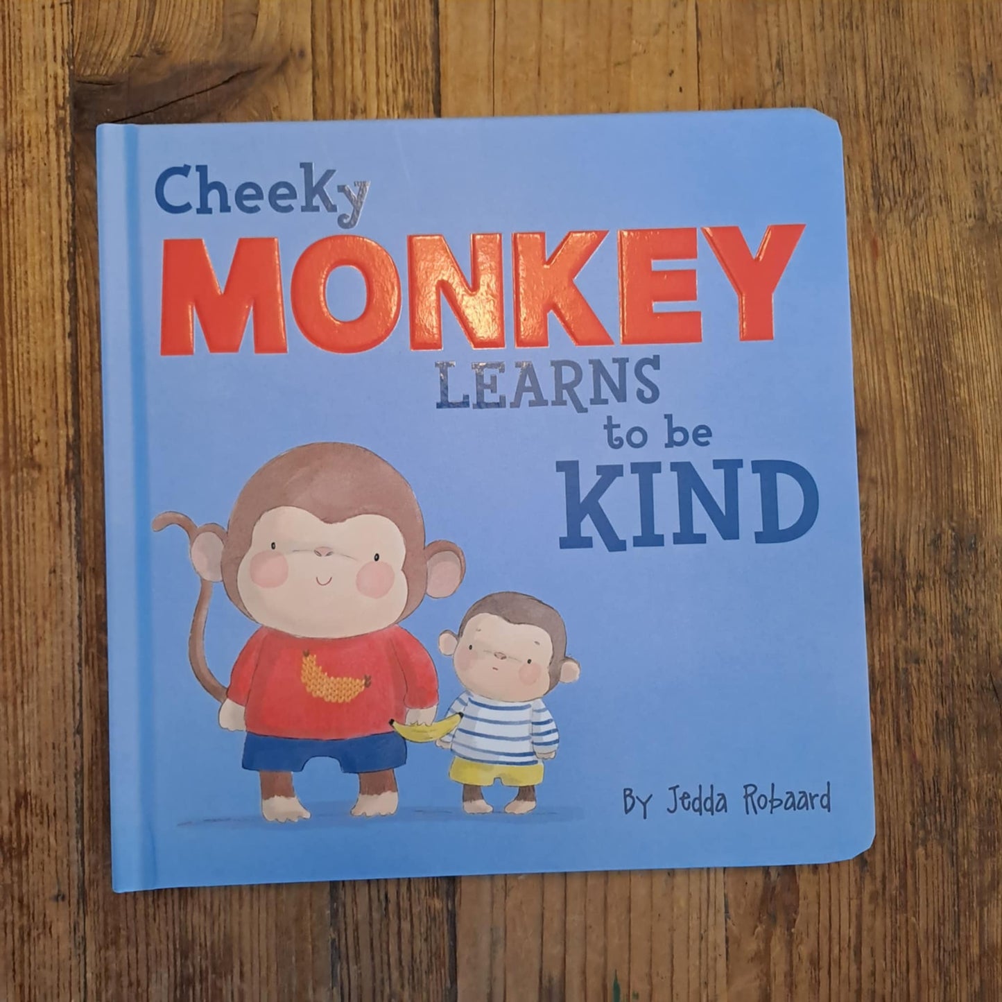 Children's book with monkey illustrations on a wooden surface
