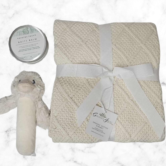 Baby blanket with plush toy and balm on a marble background
