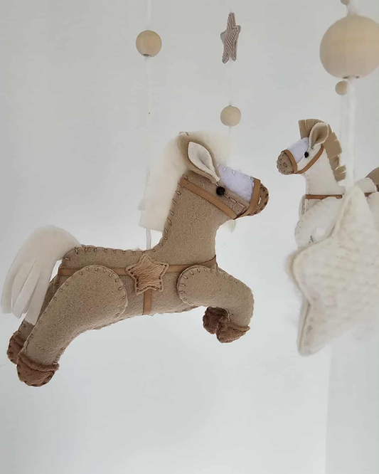 Plush horse toys hanging from a baby mobile against a white background