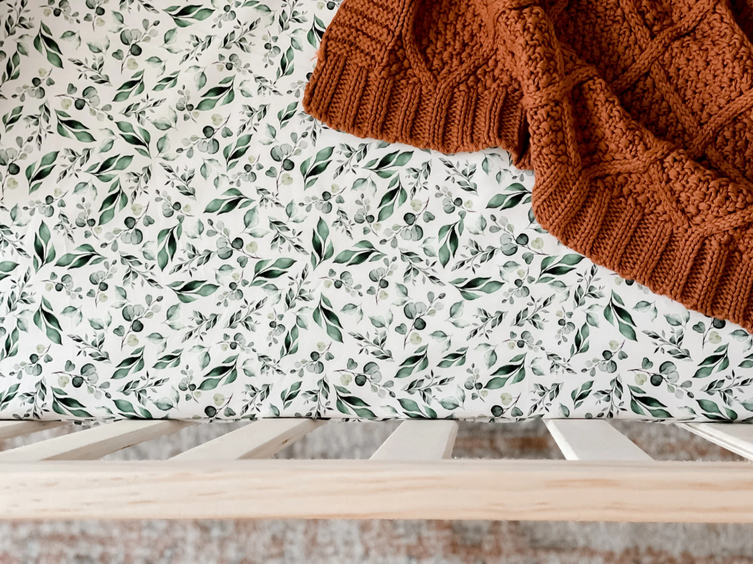 Brown knitted blanket on a surface with a leaf-patterned fabric background
