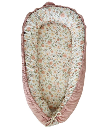 Floral-patterned baby nest with pink border on a white background