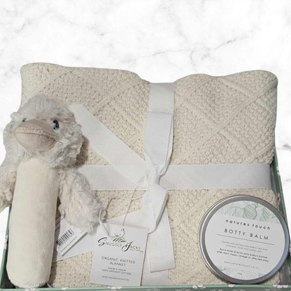 Baby gift set with plush toy, blanket, and balm on a white background