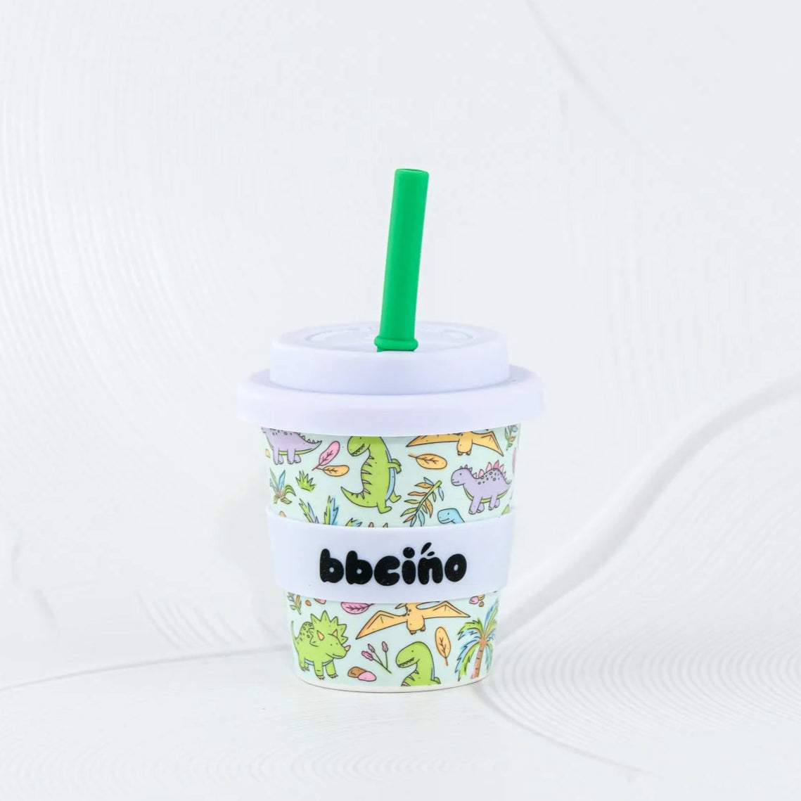 Children's cup with dinosaur pattern and straw on a white background