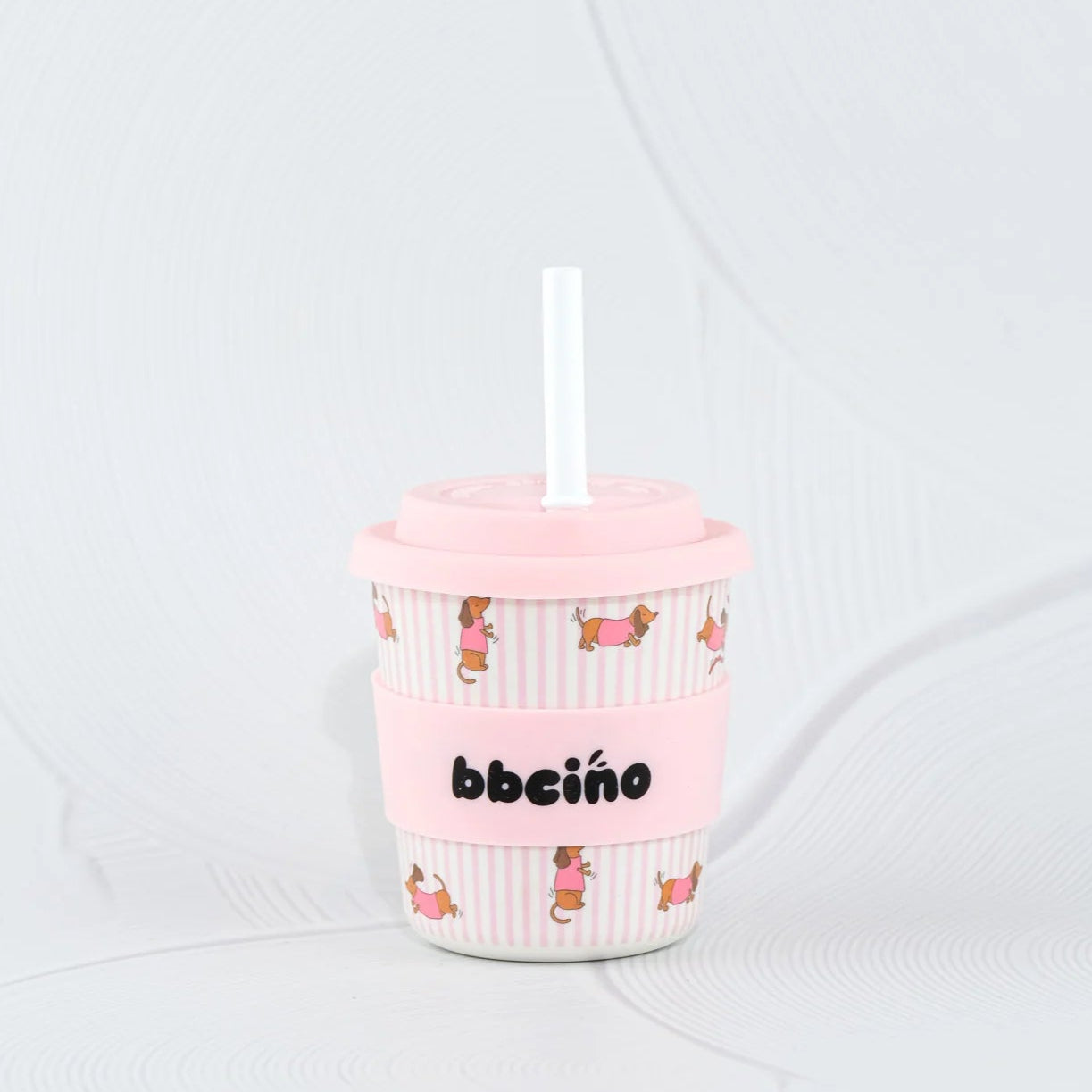 Pink tumbler with DOG design and straw on a white background