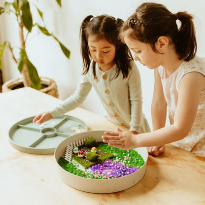 Two small girls playing with a Jellystone Tray Play with sensory kit: Fairy Garden